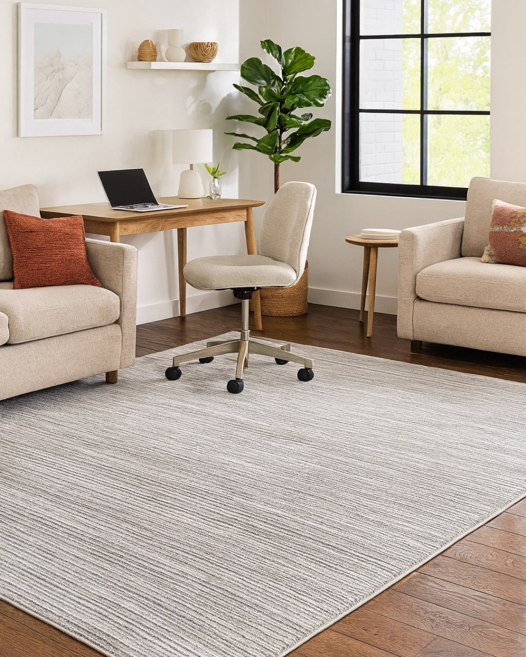 Living room with a grey striped rug, sofa, chair, and desk.