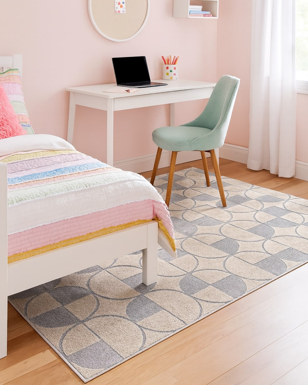Children's room with a bed, desk, and chair on a grey and beige geometric patterned rug.