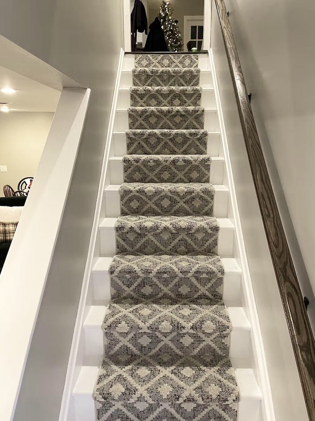 Staircase with patterned carpet leading to a room with a Christmas tree.