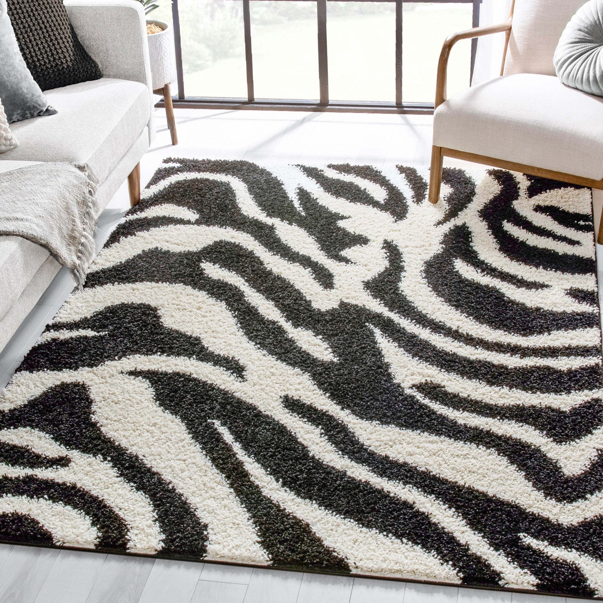 Safari Zebra Black Contemporary Shag Rug - Well Woven - A plush zebra-print rug with bold black and white stripes styled in a modern living room with light wood furniture.